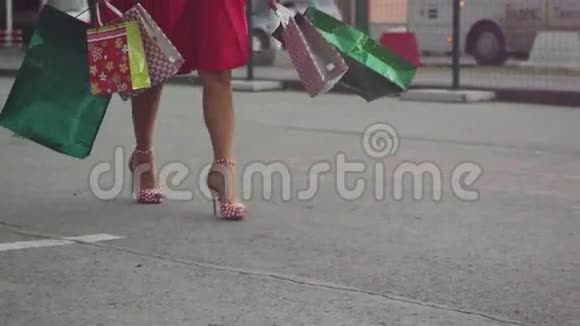 购物狂的女人穿着漂亮的衣服拿着许多购物袋慢吞吞地走在街上1920x1080视频的预览图