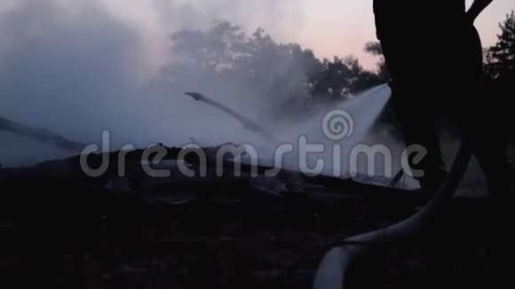 用灭火器用水灭火消防队员拿着水管晚上扑灭森林篝火视频的预览图
