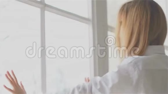 窗前漂亮的年轻女子穿着白色衬衫视频的预览图