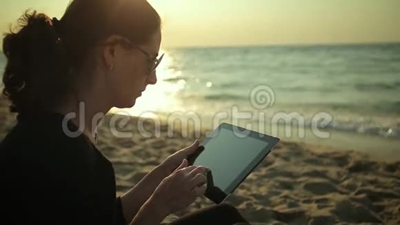 女人在海边使用平板电脑视频的预览图