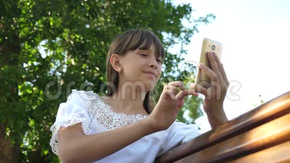 植物园里的年轻的千禧年妇女在电话显示器上做手势一个年轻女孩用智能手机视频的预览图