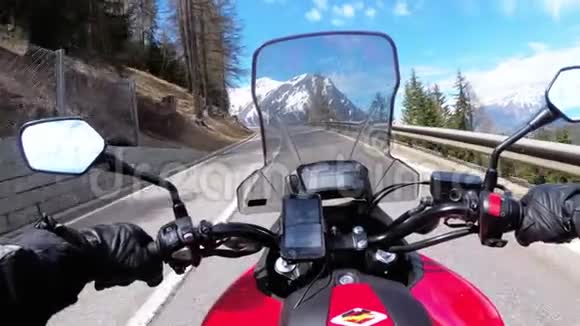 骑摩托车的人骑在瑞士雪山附近美丽的山道上视频的预览图