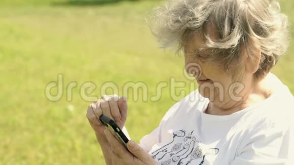 成熟的老妇人在户外拿着智能手机视频的预览图