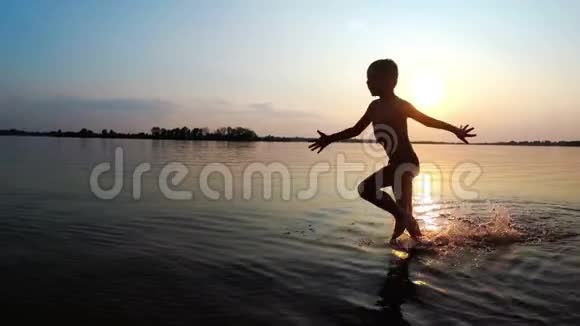 那孩子在日落时沿着海滩跑步慢动作视频的预览图