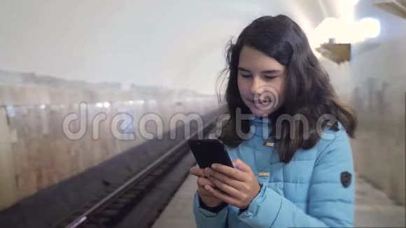 少女在地下地铁里乘地铁等待火车的到来手持智能手机小可爱视频的预览图