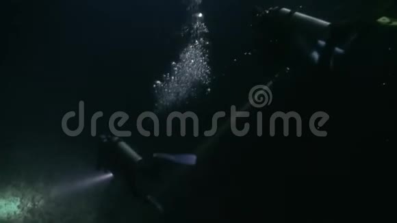 潜水者带手电筒在水下夜间底部背景视频的预览图