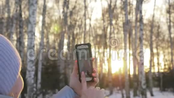 女人在树林里散步旅行者在森林的电话里被拍照女孩做自拍和沟通视频的预览图