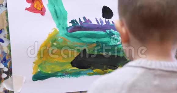 幼儿艺术家的小手用画笔画出画布坐在桌子上画画布程序视频的预览图