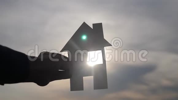 幸福家庭建设住宅理念一个男人的生活方式他手里拿着一个纸房子日落时的剪影视频的预览图