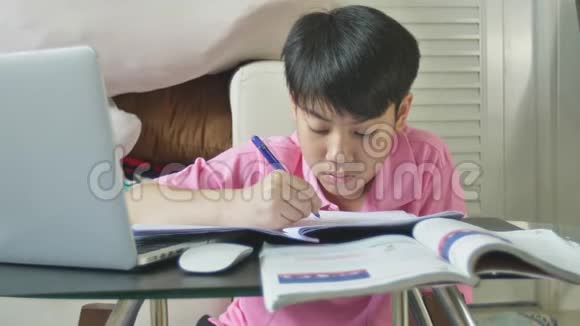 亚洲可爱的男孩在家用笔记本电脑做作业视频的预览图