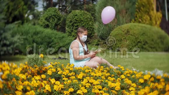 戴着呼吸器的可爱女孩在公园看书视频的预览图