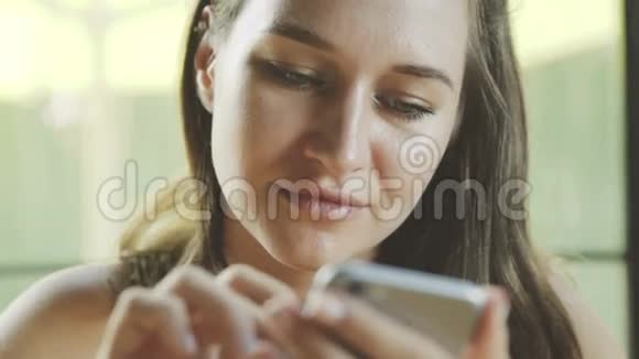 女性使用应用程序在电话和微笑在咖啡馆视频的预览图