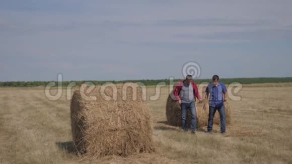团队农业生活方式智慧农业理念两个男的农民工人在田野上的草堆上散步视频的预览图