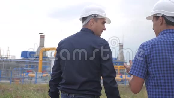 团队合作工业煤气生产站的概念慢动作录像两名戴头盔的工程师正在与视频的预览图