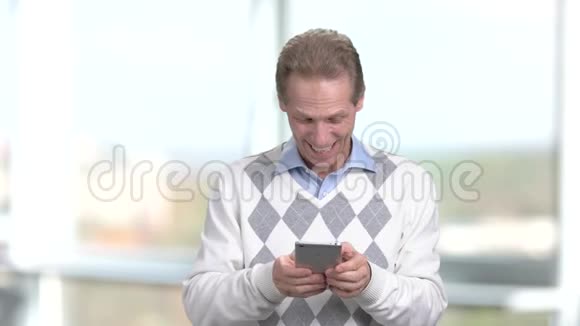 微笑成熟的男人使用智能手机视频的预览图