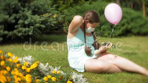 戴着呼吸器的可爱女孩在公园看书视频的预览图