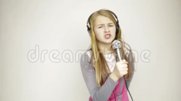 漂亮的年轻表情女孩在麦克风里唱歌视频的预览图