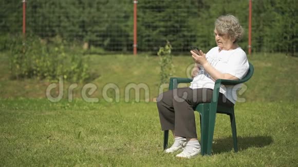 成熟的老妇人在户外拿着智能手机视频的预览图