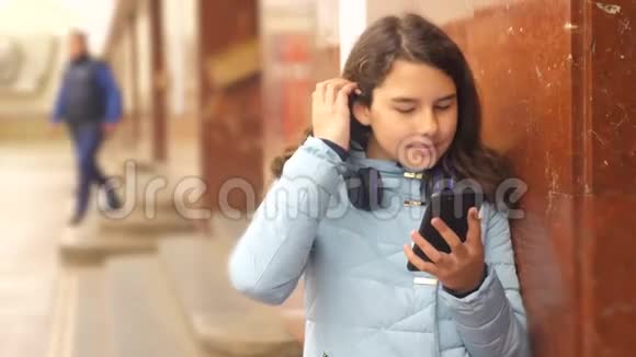 生活方式中的少女乘坐地铁地铁等待火车的到来手持智能手机视频的预览图