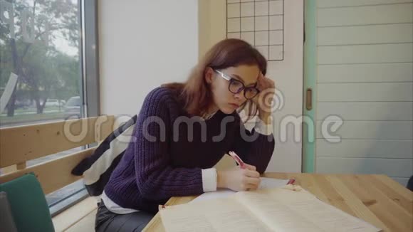 戴眼镜的女学生坐在桌子上学习视频的预览图