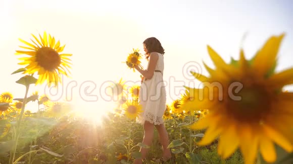 可爱的女孩在黄色的花园向日葵阳光在夏天美丽的日落小生活方式女孩向日葵视频的预览图