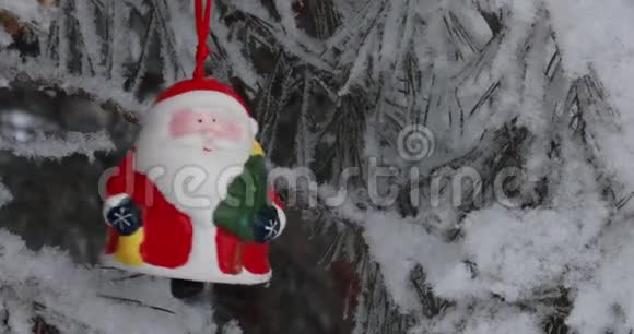 新年圣诞节和装饰品一个红色的玩具圣诞老人在森林里的树枝上摇摆下雪视频的预览图
