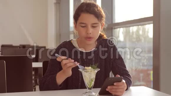 机场等待飞机航班十几岁的女孩吃沙拉看上去像智能手机在咖啡馆里上网生活方式终端视频的预览图