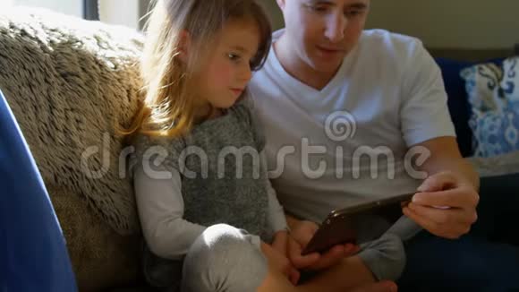 父亲和女儿在客厅里用数码平板电脑视频的预览图