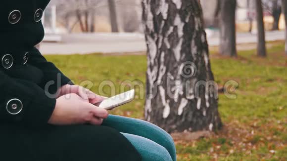 在城市公园的长凳上用手机的年轻女孩视频的预览图