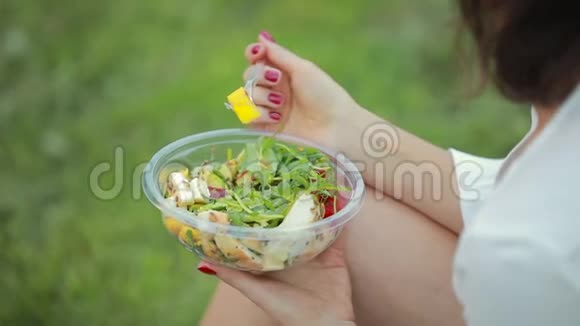 坐在草地上吃沙拉的女人视频的预览图
