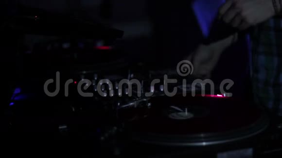 DJ在夜总会的迪斯科舞厅里刮擦唱片和在甲板上混音视频的预览图