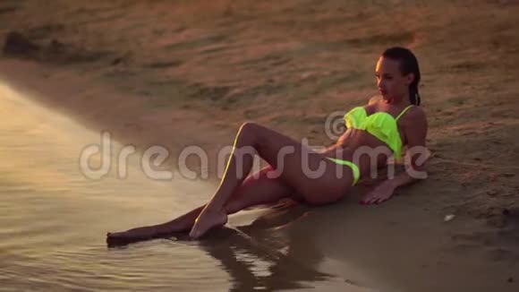 日落时穿泳衣的年轻女士视频的预览图