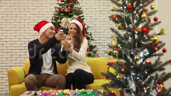 白人夫妇坐在圣诞树中间视频的预览图