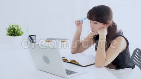 美丽的亚洲女人微笑着坐在客厅里学习在家写笔记本女孩做作业视频的预览图