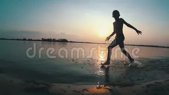 日落时沿着海滩奔跑的快乐孩子的剪影慢动作视频的预览图