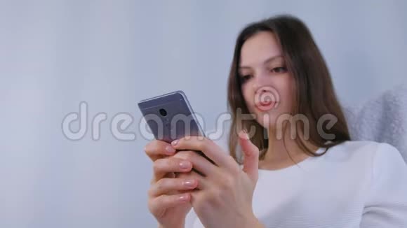 年轻的黑发女人在手机上输入信息视频的预览图