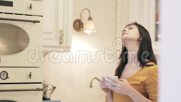 年轻漂亮的女孩在厨房里喝咖啡视频的预览图