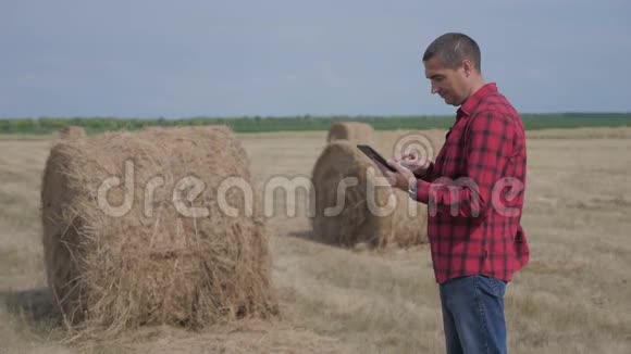 智慧农业理念男子工人农民的生活方式研究干草堆在一个领域的数字平板电脑慢慢慢慢视频的预览图