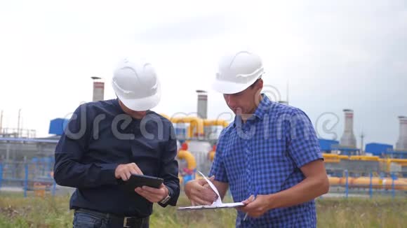 团队合作工业煤气生产站的生活方式理念慢动作视频两名戴头盔的工程师正在学习视频的预览图