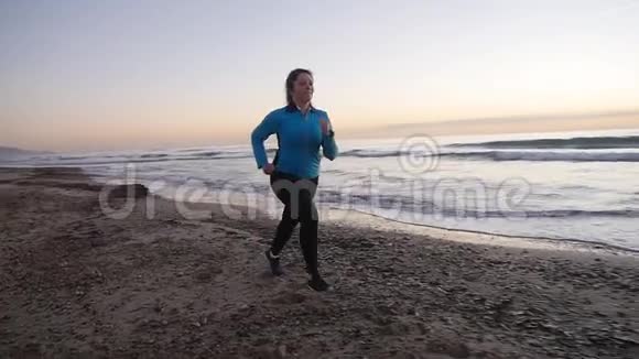 日落时在海滩上奔跑的女人健身理念视频的预览图