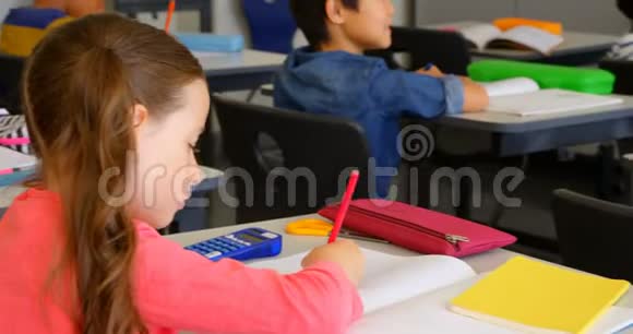 快乐的高加索女学生在4k学校的教室里书桌上学习视频的预览图