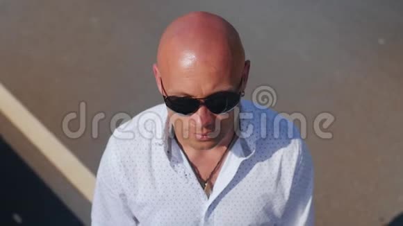 一个戴太阳镜的秃头男人抬头的肖像近距离射击视频的预览图