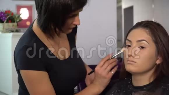 美容院年轻漂亮的女孩模特坐在椅子上化妆师给女孩化妆视频的预览图