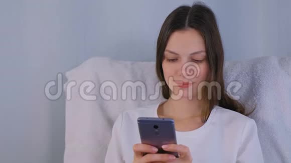 年轻的黑发女人在手机上输入信息视频的预览图