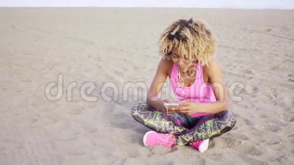 坐在沙滩上听音乐的女人视频的预览图