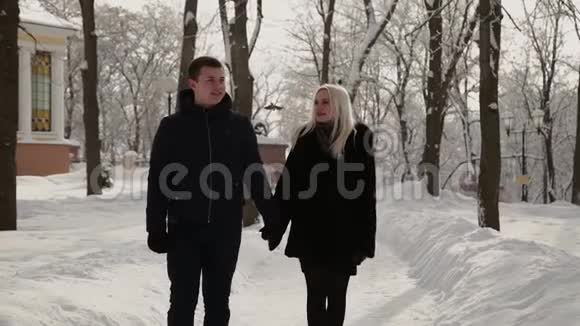美丽的年轻夫妇牵着手在公园里散步视频的预览图
