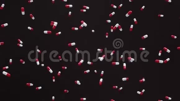 落在黑色背景下的红白药丸循环视频的预览图