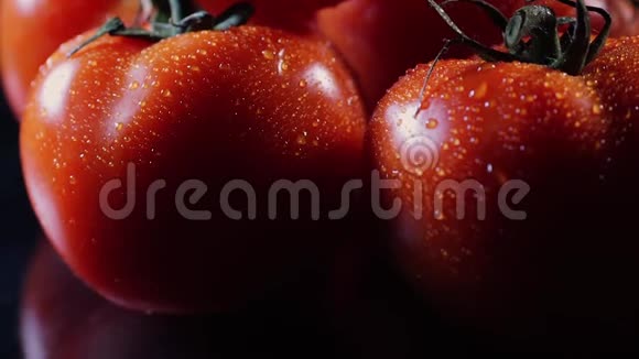 许多成熟的新鲜番茄躺在黑色的玻璃桌上绕着它的轴旋转特写新鲜蔬菜视频的预览图