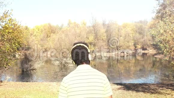 带着耳机听湖边音乐的人的后景视频的预览图