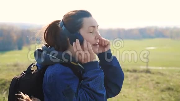 中年女性游客带着背包戴着耳机听音乐用生活方式看智能手机视频的预览图